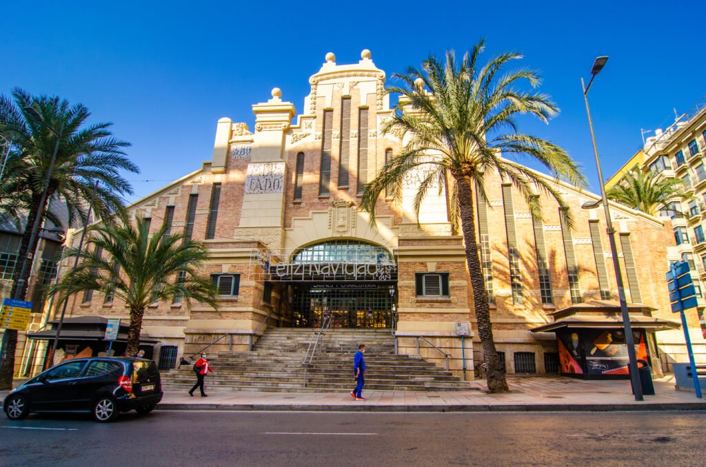 A lively scene at Alicante’s Mercado Central with vendors selling fresh fruits, vegetables, meats, and regional specialties.